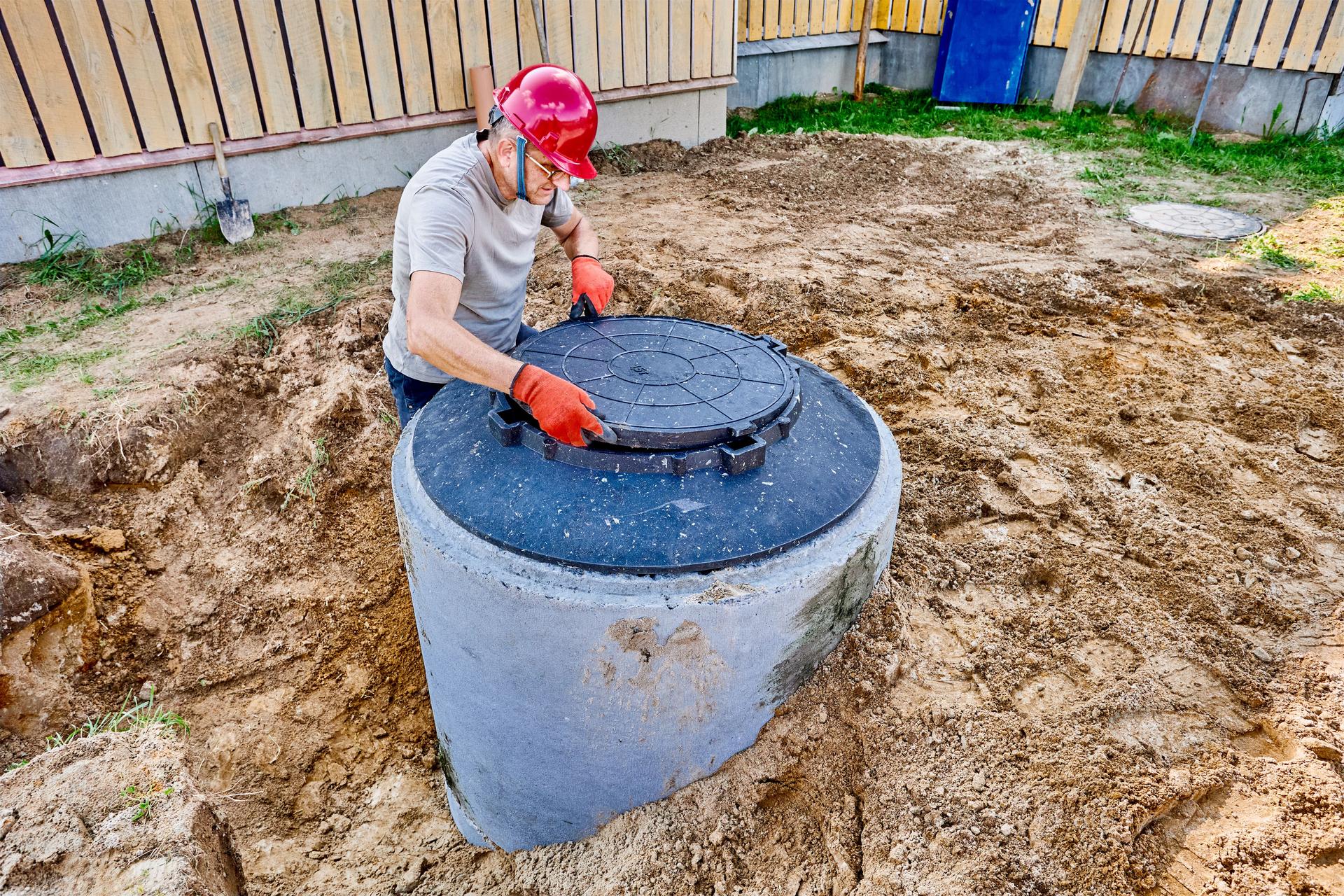 An engineer installs manhole cover or septic tank lid on concret